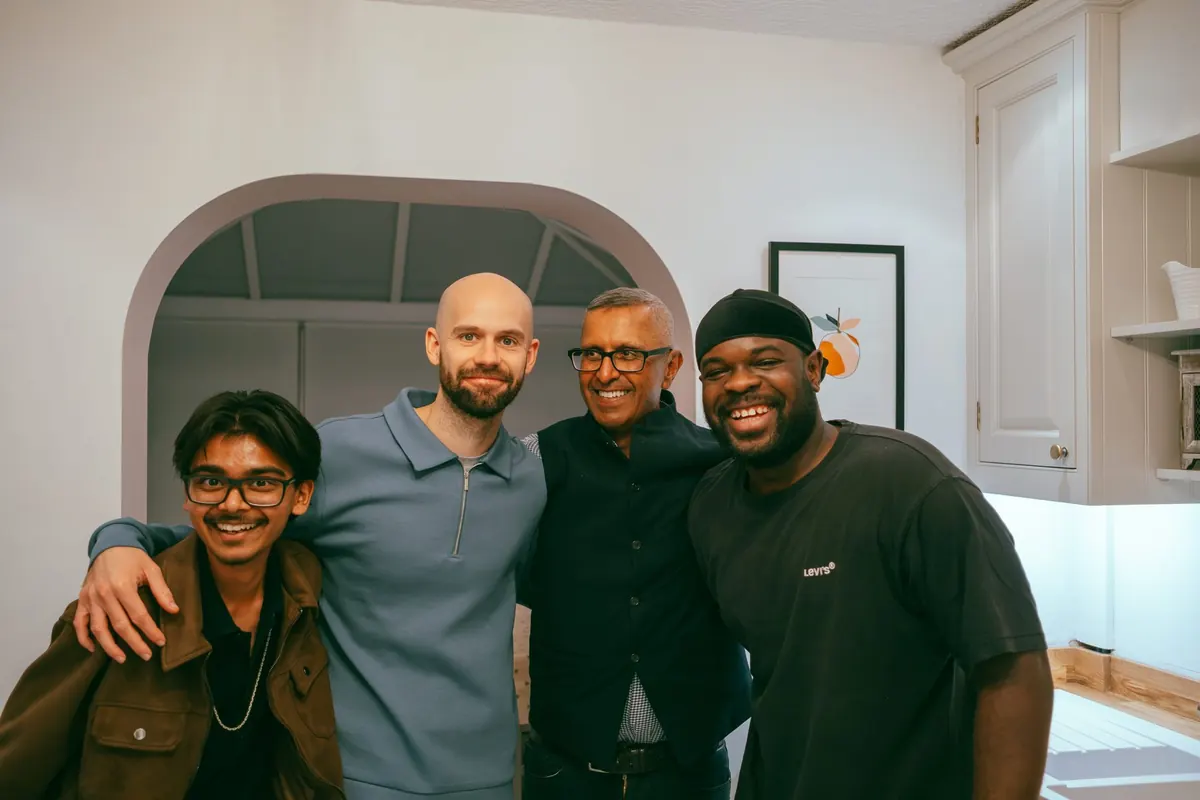 Four men laughing with their arms around each other at a Life Group in a home kitchen