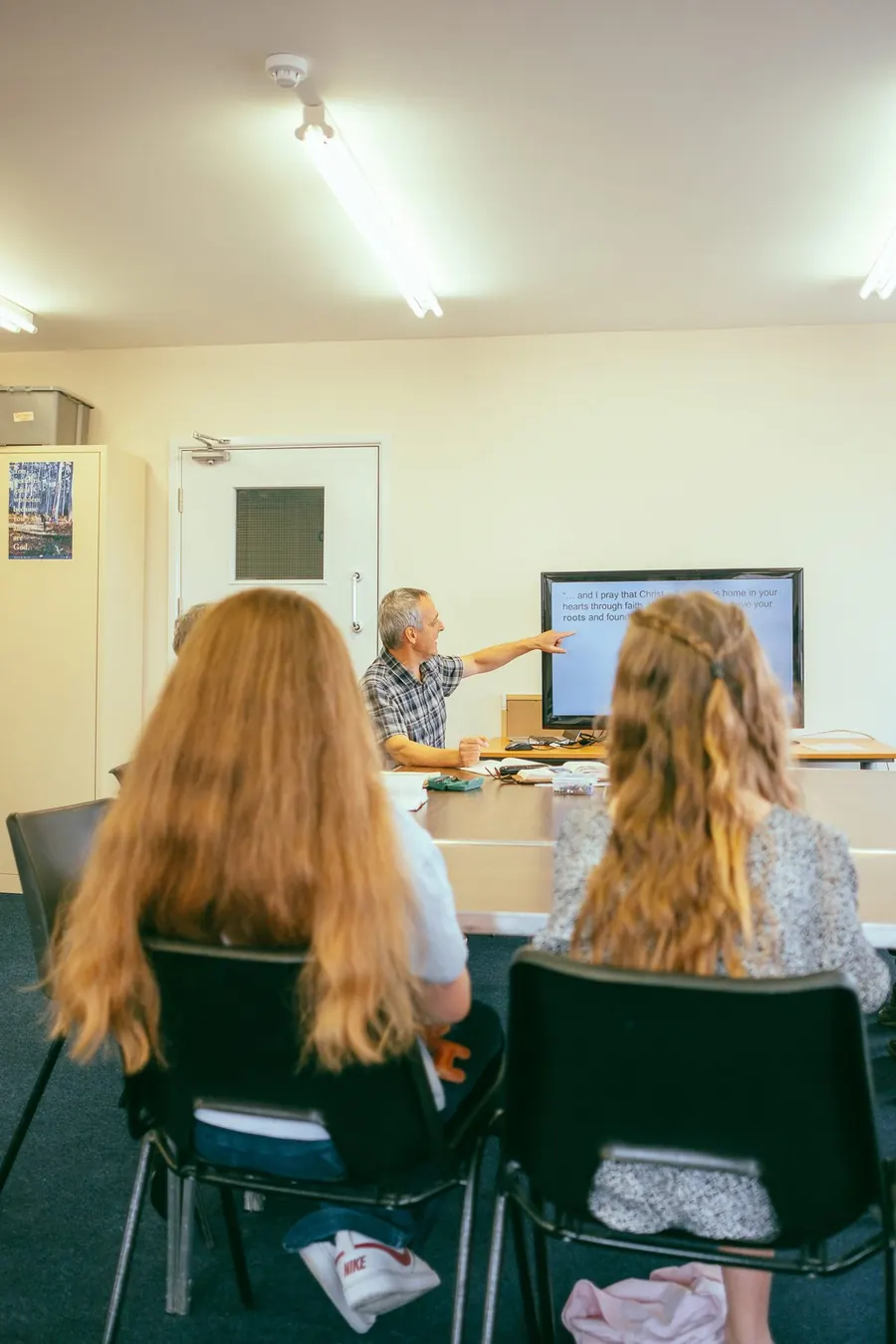 A small group sat around a table listening as a leader points to a screen