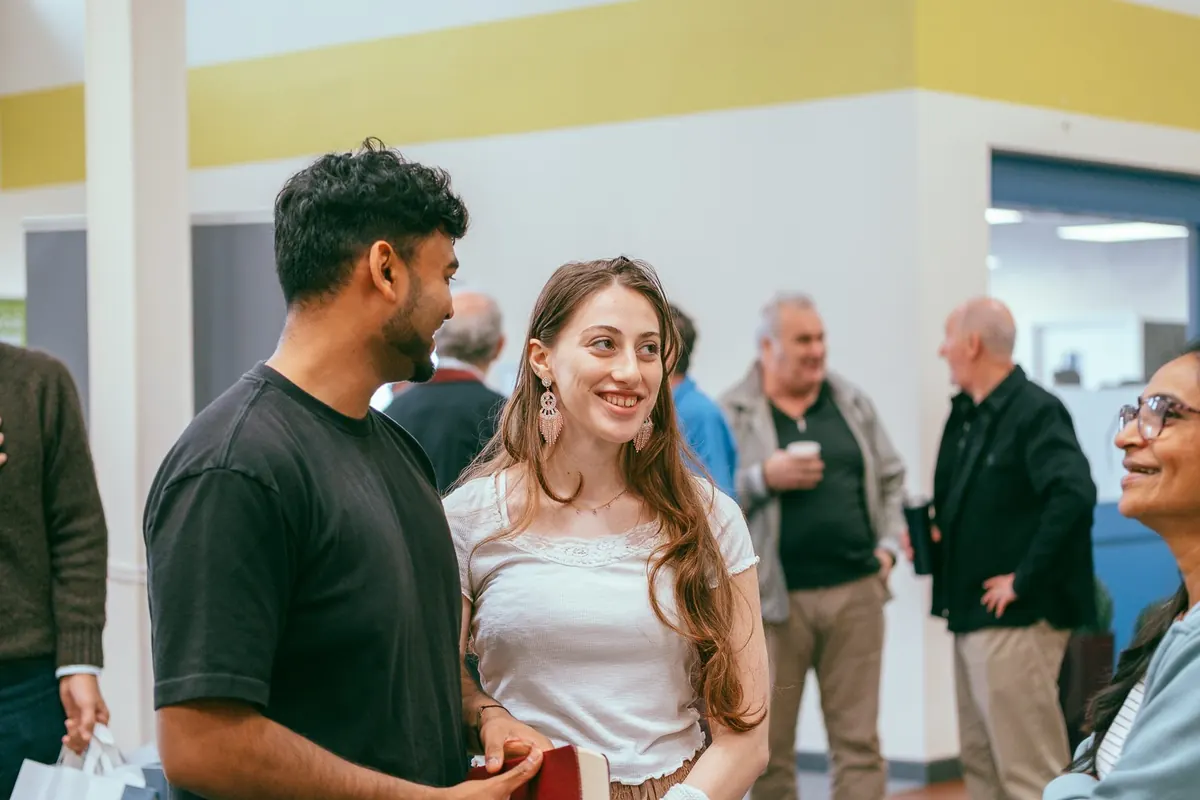 A young man and woman chatting among the congregation in the church hall