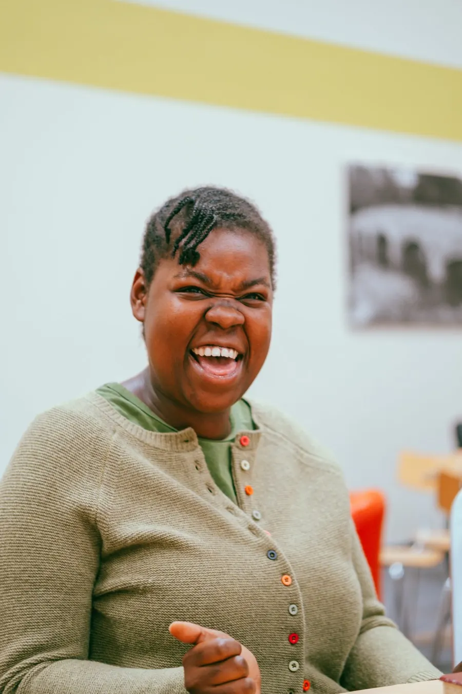 A woman in a green cardigan laughing during a Sunday gathering