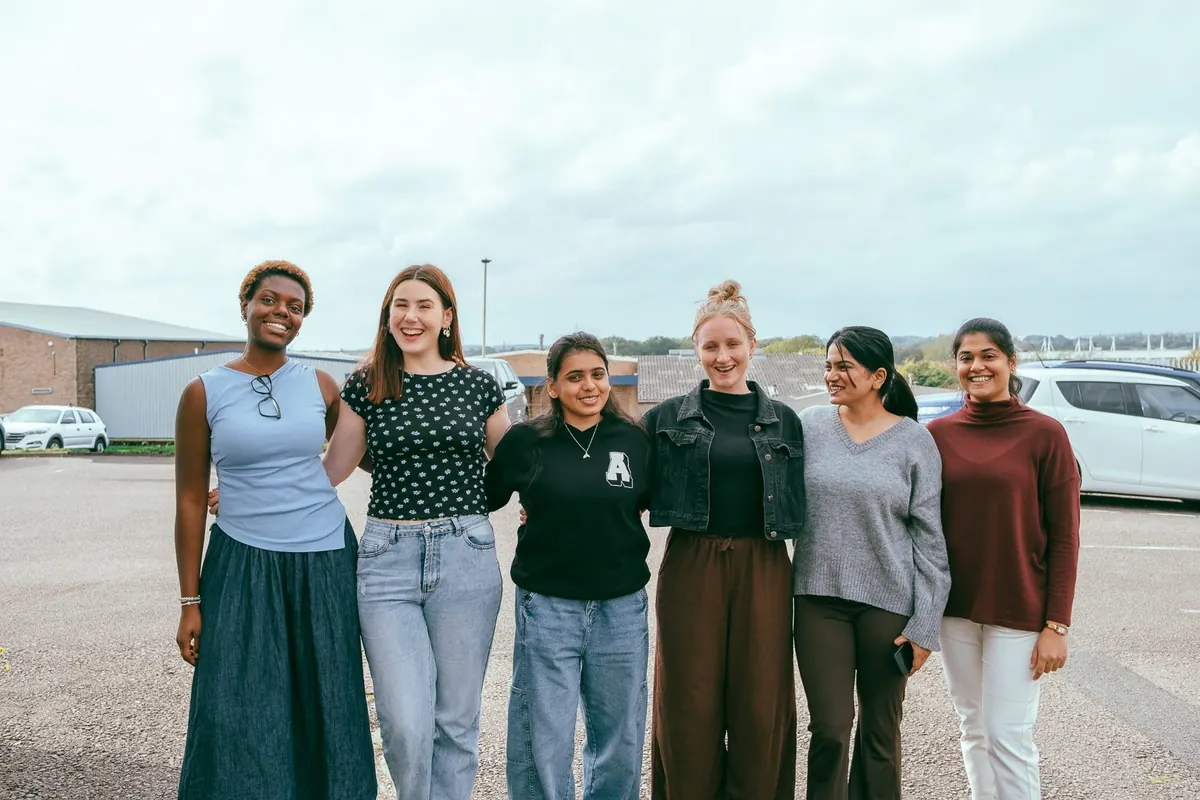Six young women from the church smiling together outside on a grey Sunday morning